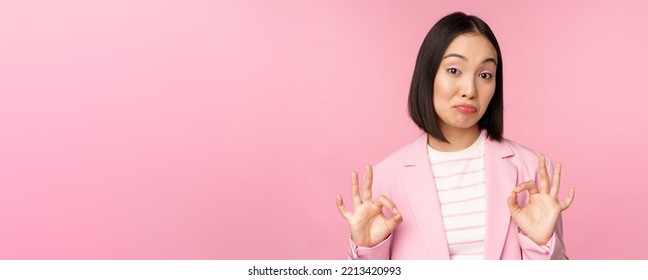 Not Bad. Impressed Businesswoman, Asian Office Lady Showing Okay Sign And Nod In Approval, Standing Over Pink Background