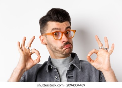 Not bad. Impressed man in stylish glasses showing okay signs and nod in approval, prase good thing, making compliment, standing on white background - Shutterstock ID 2094334489