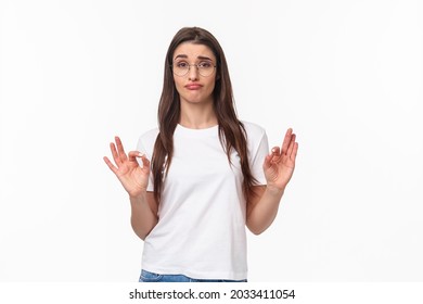 Not Bad, Very Cool. Waist-up Portrait Of Impressed Young Pretty Woman In Glasses, Smirk And Show Okay Signs, Pleased With Great Choice, Rate Awesome Product, Standing White Background