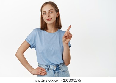 Not So Fast. Smiling Beautiful Teen Girl With Blond Hair And Blue Eyes, Shaking Finger, Pointing At Smth, Teach Lesson, Tell Rule, Standing Against White Background