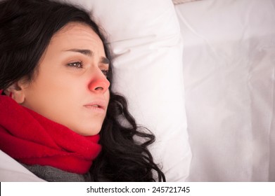 Not Feeling Too Great. Closeup Image Of Young Sick Woman Lying In Bed With Red Nose In Thick Scarf And Looking Away In Frustration At Copy Space