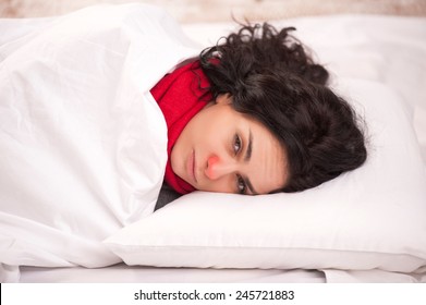 Not Feeling Too Great. Closeup Image Of Young Sick Woman Lying In Bed With Red Nose In Thick Scarf And Looking At Camera In Frustration At Copy Space