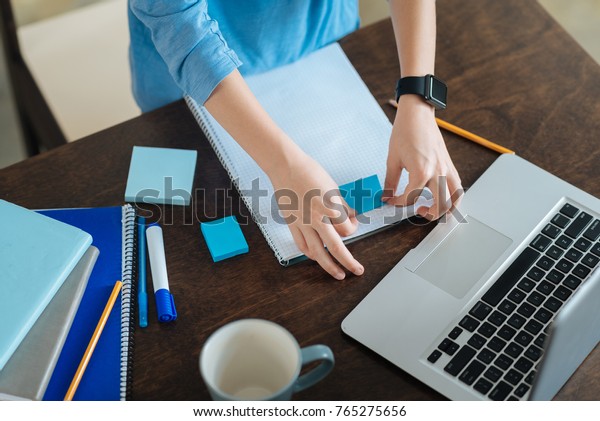 Not to forget. Close up of a sticky note being put on a copybook by a nice cute pleasant boy