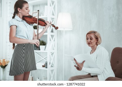 Not Impressed. Unhappy Cheerless Woman Listening To Her Student While Being Not Impressed With Her Play