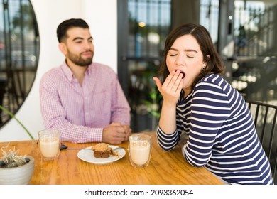 I'm Not Interested. Bored And Tired Young Woman Yawning While Listening To A Boring Man During A Date At The Coffee Shop