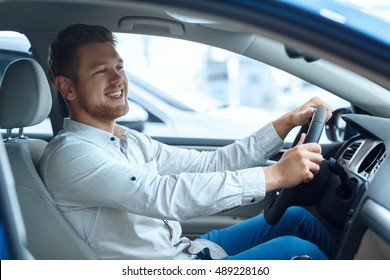 Not Leaving Without This Car! Shot Of A Happy Handsome Man Smiling Joyfully While Trying Out A New Car At The Dealership