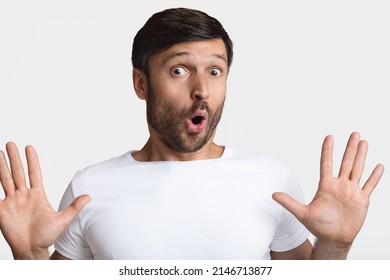 It's Not Me. Scared Man Showing His Hands Looking At Camera In Shock With Opened Mouth Expressing Fear Standing Over White Studio Background. Portrait Of Afraid Male