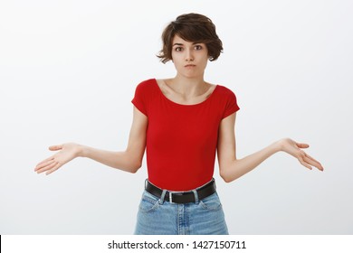 Not my problem sorry cannot help. Confused unaware awkward cute female coworker pixie short haircut acting uncertain pouting troubled answer shrugging hands spread sideways clueless white background