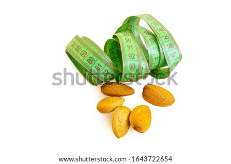 not peeled almonds and green centimeter letta on a white isolated background. about the benefits of nuts when losing weight