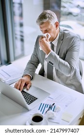 It Is Not Productive To Be Sick At Work. Cropped Shot Of An Ill Businessman Blowing His Nose In The Office While Working On A Laptop.