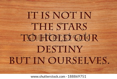It is not in the stars to hold our destiny but in ourselves - quote by William Shakespeare on wooden red oak background