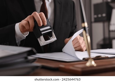 Notary stamping document at table in office, closeup