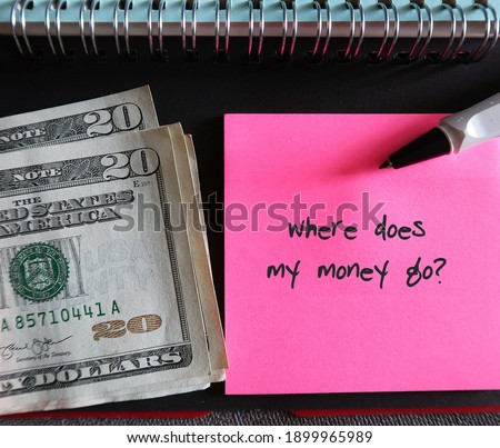 Note book, cash dollars money, pen, pink note with text written WHERE DOES MY MONEY GO?, concept of find out spending leaks to fix them and boost saving