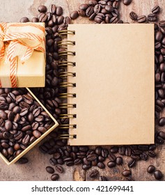 note book with coffee beans on wooden background ,top view