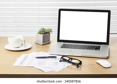 A note book, laptop, glasses, mouse, vintage compass, coffee cup, pen, graph paper(document) on the office desk(table) behind white blind.