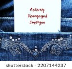 Note in jean pocket with handwritten text Actively Disengaged Employee - refers to employees who are unhappy at work and busy undermining workplace by getting others to share in their discontent