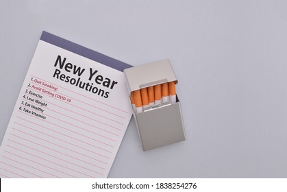 Note Pad With New Year Resolutions And A Pack Of Cigarettes On Gray Background