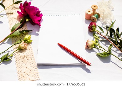 Note pad with pen, surrounded by flowers