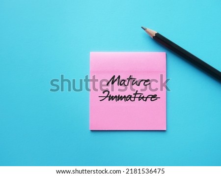 Note paper on blue background with handwritten text cross off IMMATURE to MATURE, means to improve from being person who thinks and acts like child to be mature, think and act like adult