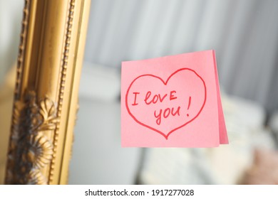 Note with phrase I Love You attached to mirror