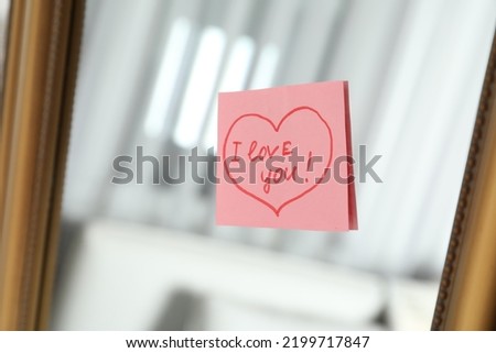 Note with phrase I Love You attached to mirror