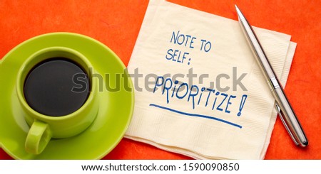 Note to self - prioritize. Handwriting on a napkin with a cup of coffee. Business, lifestyle and personal development concept.