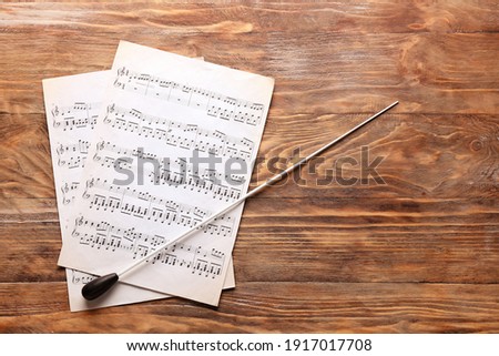 Note sheets and conductor's stick on wooden background