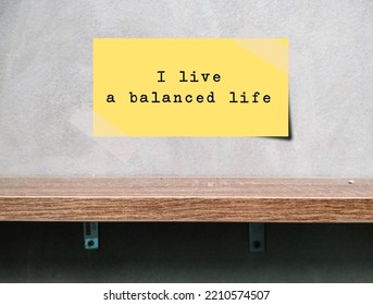 Note Stick On Wall Over A Shelf With Text Written I LIVE A BALANCED LIFE, Positive Mantra Affirmation To Remind Oneself That Living Well-balanced Life Is Crucial For Healthy, Happy And Well-being Life