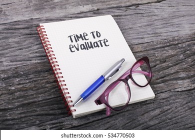 Note with Time To Evaluate on the wooden background