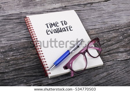 Note with Time To Evaluate on the wooden background