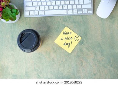 note with words HAVE A NICE DAY with smile and coffee in papper cup, keyboard, cactus and mause on a wooden table. concept of good start to day. top view of the desktop. Flat lay - Powered by Shutterstock