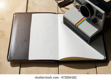 Notebook with camera  on wooden table.