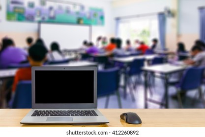 Notebook Computer On The Table, Blur Image Of Classroom As Background.