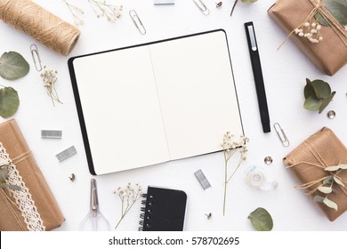 Notebook With Craft Boxes And Green Branches On White Background. Wedding Planning. Flat Lay, Top View