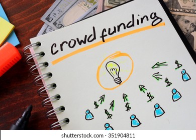 Notebook with crowd funding  sign on a table. Business concept.