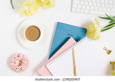 Notebook for daily planning with breakfast serving on a white background, a cup of coffee, a donut, flowers and a gift box with a bow. The concept of daily planning of life, work, study. Mother's Day