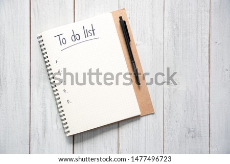 Notebook with an to do list on white wooden background and pen with copy space, planning and design concept.