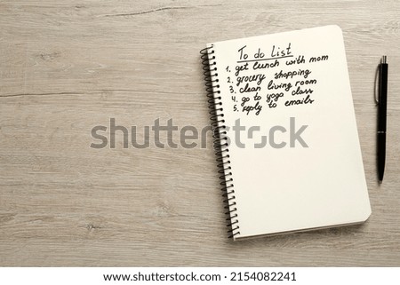 Notebook with to do list and pen on white wooden table, flat lay. Space for text