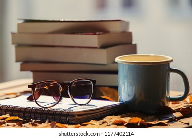 Notebook With Glasses Cup And Books, Maple Leaves On Wooden Table. Side View. Fall Season