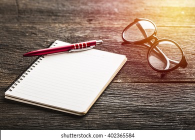 Notebook and glasses and red pen on table. Vintage filter - Powered by Shutterstock