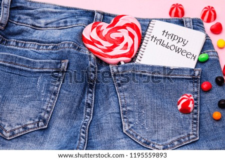 notebook with halloween text and lollipop in jeans pocket