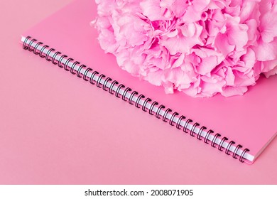 Notebook and hydrangea with copy space on pink background. Stylish background for beauty, fashion and business sphere