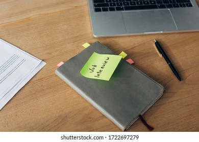 Notebook with job interview lettering on sticky note near laptop and documents on table - Shutterstock ID 1722697279