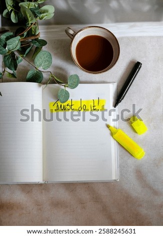 Notebook with just do it text and coffee cup .Business concept 