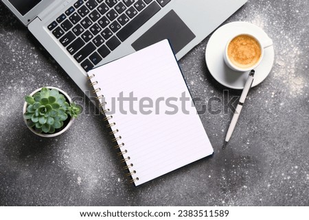 Notebook with laptop and cup of tasty coffee on grey background
