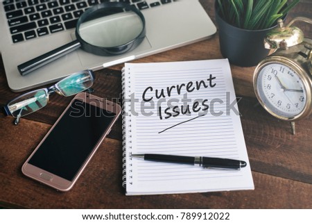 notebook, laptop, smartphone, clock and pen with CURRENT ISSUES word on a wooden background. current issues concept