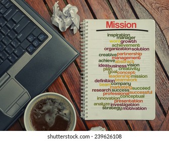 notebook lying on the table with the written words associated with the Mission , on the table are also laptop and cup of coffee, notes made in the form of the cloud of words