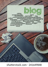 notebook lying on the table with the written words associated with the blog , on the table are also laptop and cup of coffee, notes made in the form of the cloud of words 