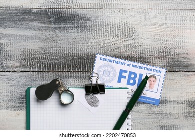 Notebook With Magnifier And Document Of FBI Agent On Wooden Background