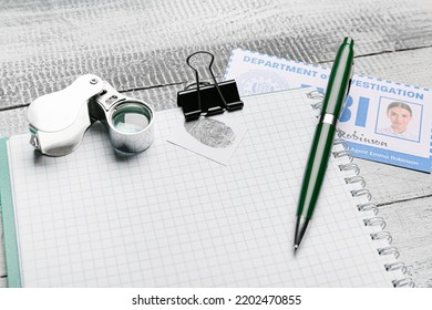 Notebook With Magnifier And Document Of FBI Agent On Wooden Background, Closeup